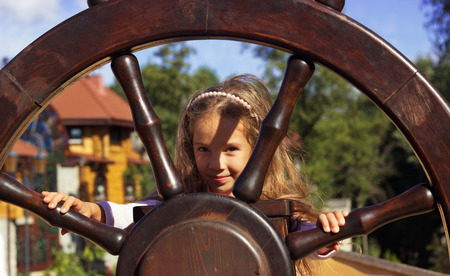 Cute girl holds a Steering wheel of the shipの写真素材