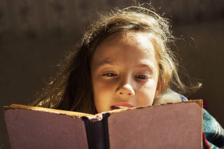 portrait of cute curly girl reading bookの写真素材