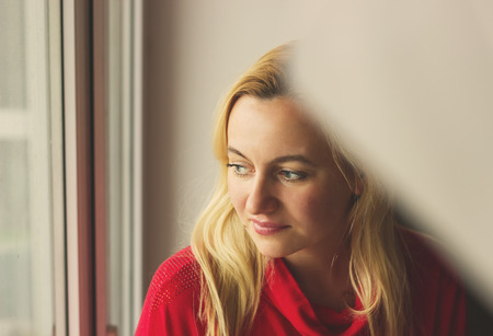 Toned portrait of Beautiful blonde woman sitting by the window.の写真素材