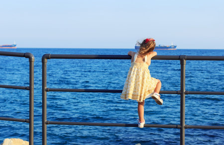 Little girl is looking  at the sun dive in the wide seaの写真素材