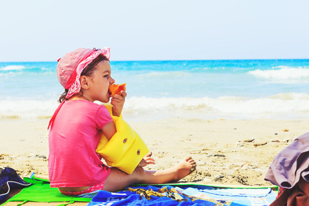 cute toddler eating fresh summer peach  on the beachの写真素材
