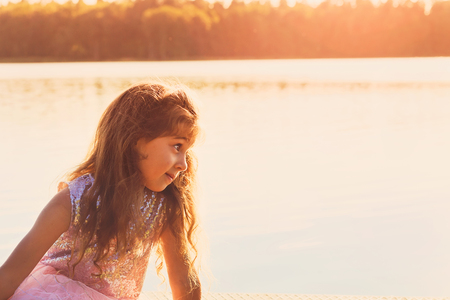 Little girl is looking at the sunset in the seasideの写真素材