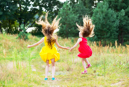 Two beautiful little girls  jumping and dancing at sunny summer day. Happy kids conceptの写真素材