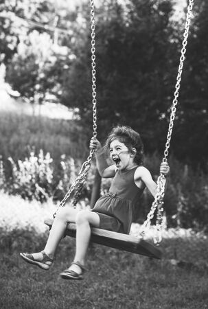 Black and white portrait of Beautiful little girl smiling on swing at summer day, Happy childhood concept. Soft focused.の写真素材