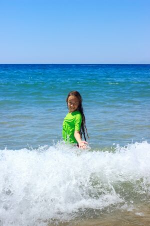 Teen girl swimming on tropical beach. Child plays on ocean waves. Active water sports for Teenager.の写真素材
