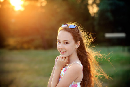 Beautiful Teen Girl is smiling and enjoying nature in the park at Summer sunsetの写真素材