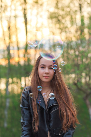 Cute teen Girl blowing soap bubbles at the field at spring day.
