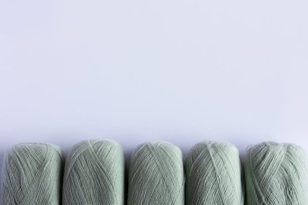 Light green yarn threads on a blue background for knitting. Flat lay