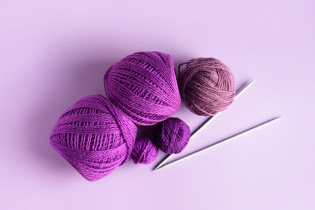 Purple lilac and pink knitted wool on a lilac background for knitting warm clothes and hobbies...