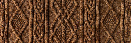 Knitted brown background banner. Large knitted fabric with a pattern. Close-up of a knitted blanket
