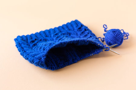Knitting blue warm clothes with knitting needles and blue balls of thread on an orange background