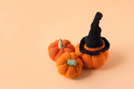 Knitted orange pumpkins with a black witch hat on an orange background, autumn composition, front view. Halloween concept.の写真素材