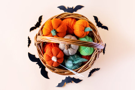Knitted orange green and beige pumpkins in a basket and black batson on a orange background, knitting hobby, autumn composition. Halloween concept.の写真素材