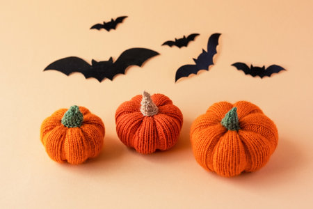Knitted orange pumpkins and black bats on an orange background, autumn composition, front view. Halloween concept.の写真素材
