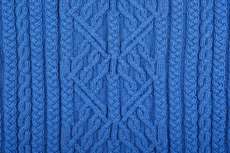 Knitted blue background. Large knitted fabric with a pattern. Close-up of a knitted blanket.
