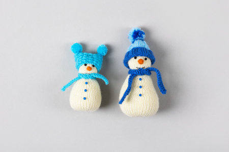 Two funny knitted snowmen in blue hats and scarves on a gray background. Merry Christmas and New Year 2023 greeting cardの写真素材