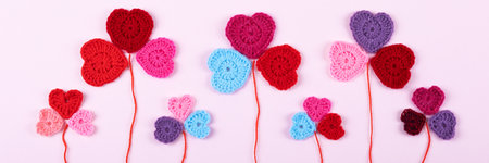 Multicolored crocheted hearts are laid out in the shape of a flower clover on a lilac background. Happy Valentines Day, Mothers Day and birthday greeting card. Bannerの写真素材