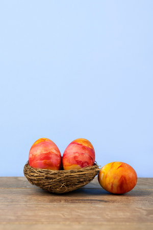 Three Easter eggs in a decorative nest of sisal on a wooden background. Happy Easter concept. Greeting card.の写真素材