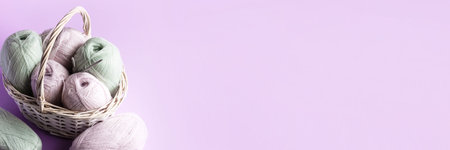 Pink and green balls of thread in a basket on a pink background for knitting warm clothes and...