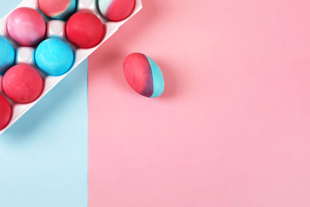 Painted Easter eggs in viva magenta and blue in a white box on a blue and pink background with a place for text. Happy Easter concept. Greeting card, copy spaceの写真素材