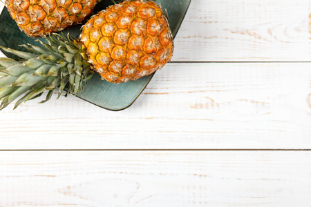 Juicy pineapples in a green plate on a white wooden background. Healthy, detox and dietary nutrition...