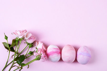 Pale pink Easter eggs with a sprig of pink roses on a pink background. Happy Easter concept. Greeting card, copy spaceの写真素材