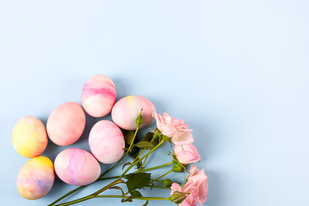 Pale pink Easter eggs with a sprig of pink roses on a pink background. Happy Easter concept. Greeting card, copy spaceの写真素材