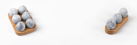 Grey Easter eggs in a wooden stand on a gray background. Minimal Easter concept. Bannerの写真素材