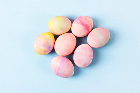 Painted Easter eggs in pink yellow and green on a blue background with a place for text. Happy Easter concept. Greeting card.の写真素材