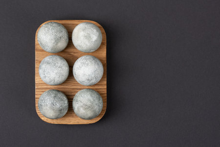 Grey Easter eggs in a wooden stand on a black background. Minimal Easter conceptの写真素材
