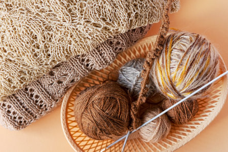 Beige and brown balls of thread in a beige basket with knitting needles for knitting warm clothes, knitting hobbyの写真素材