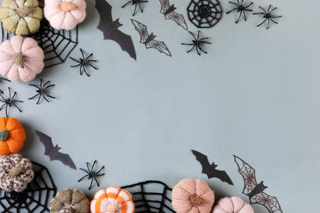 Happy Halloween holiday concept. Frame made of Halloween decorations, spiders, bats, knitted webs, pumpkins on green background. Flat lay, top viewの写真素材