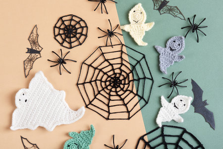 Halloween decorations, ghost, spiders, bats, knitted webs on green and beige background. Flat lay, top viewの写真素材