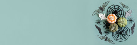 Halloween concept. Halloween decorations, ghost, spiders, bats, knitted webs, pumpkins on green background. Halloween greeting card mockup with copy space. Flat lay, top view, bannerの写真素材