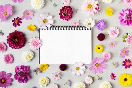 Creative layout made of flowers asters, dahlias, calendula and notebook with clean page. Colorful autumn flower background with space for text. Nature trendy decorative design. Flat lay.の写真素材