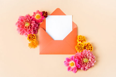 Orange envelope with clean white sheet for your text and autumn flowers pink dahlias and marigolds...