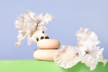 Wood stones and white iris flowers on green podium. Concept scene stage showcase for new product,...