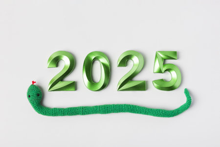 Knitted toy green snake and green numbers. The symbol of the year 2025 on a gray background.の写真素材