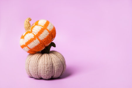 Knitted beige orange and striped pumpkins on purple background. Knitted autumn story with your own hands. Concept of autumn, Thanksgiving, harvest, Halloweenの写真素材
