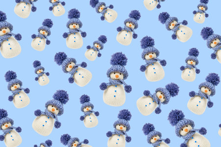 Fabulous Christmas pattern of knitted snowmen on a blue background. Winter fairy tale story with your own hands, hobby. Merry Christmas and New Year 2025 greeting cardの写真素材