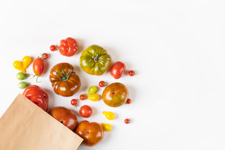 Red, green, yellow and striped tomatoes in paper bag. Flat lay. Healthy food, fresh healthy vegetables from the gardenの写真素材
