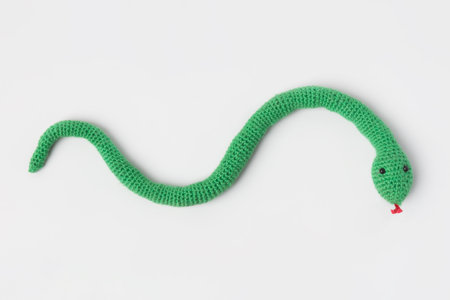 Knitted toy green snake on gray background.. Symbol of the year 2025.の写真素材
