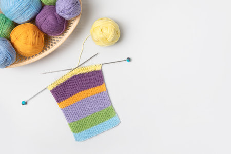Yellow, green, blue, orange and lilac colors knitting balls in basket with knitting needles and...