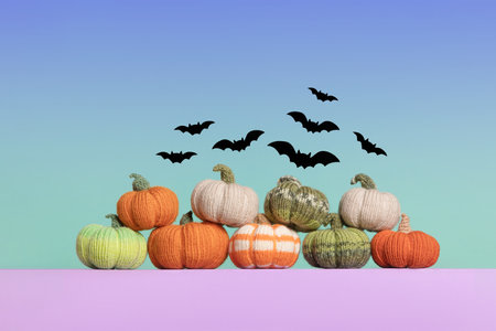 Knitted orange, green and gray pumpkins with black bats on blue green gradient background, autumn composition, front view. Halloween concept.の写真素材