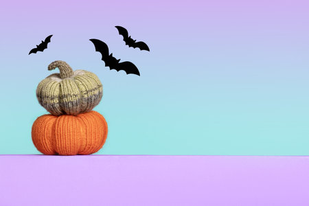 Knitted orange and green pumpkins with black bats on purple green gradient background, autumn composition, front view. Halloween concept.の写真素材