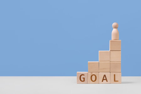 Wooden cubes with the words goal and wooden man figurine are a symbol of success, business progress, strategic development of a company, startup. Business conceptの写真素材