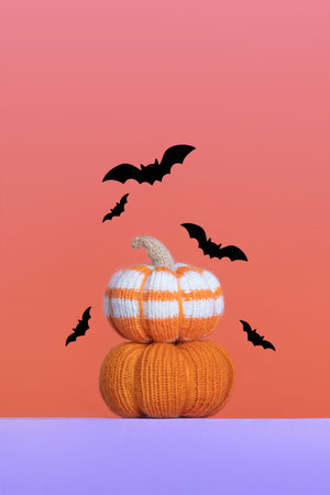 Knitted orange pumpkins with black bats on purple orange gradient background, autumn composition, front view. Halloween concept.の写真素材