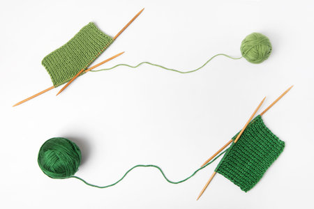 Green knitted wool on gray background with knitting needles for knitting warm clothes and hobbies...