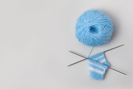 Blue knitted wool on gray background with knitting needles for knitting warm clothes and hobbies...