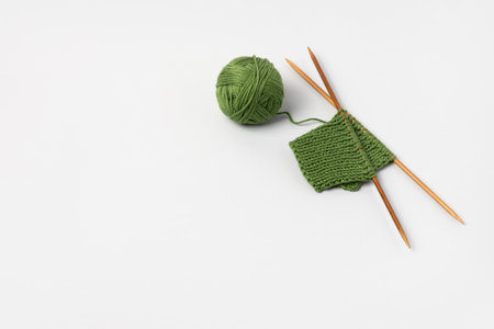 Green knitted wool on gray background with knitting needles for knitting warm clothes and hobbies needleworkの写真素材